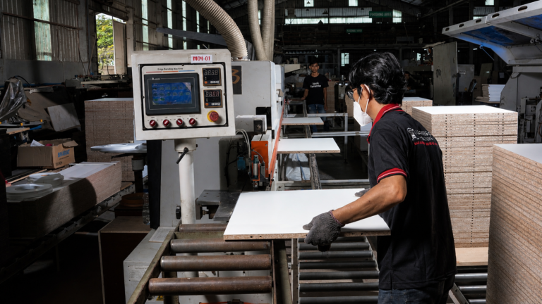 Operator menjalankan mesin edge banding untuk proses finishing furniture custom di workshop Lunarsol.